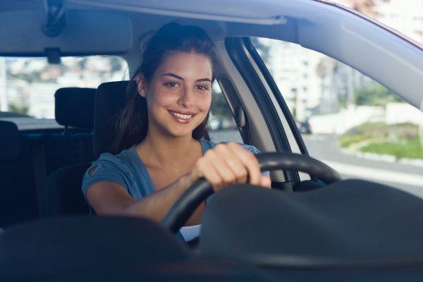 Jovem dirigindo carro com volante do lado esquerdo, imagem representando o processo para tirar CNH no Brasil em 2026