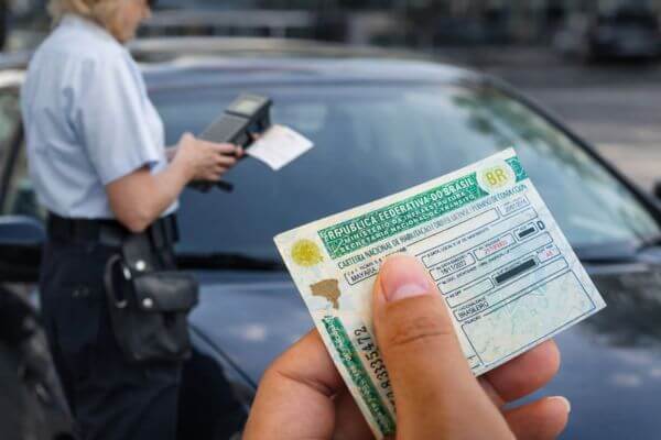 Motorista segurando CNH durante fiscalização de trânsito relacionada a pontos na carteira