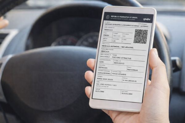 motorista consultando licenciamento atrasado no CRLV digital pelo celular dentro do carro